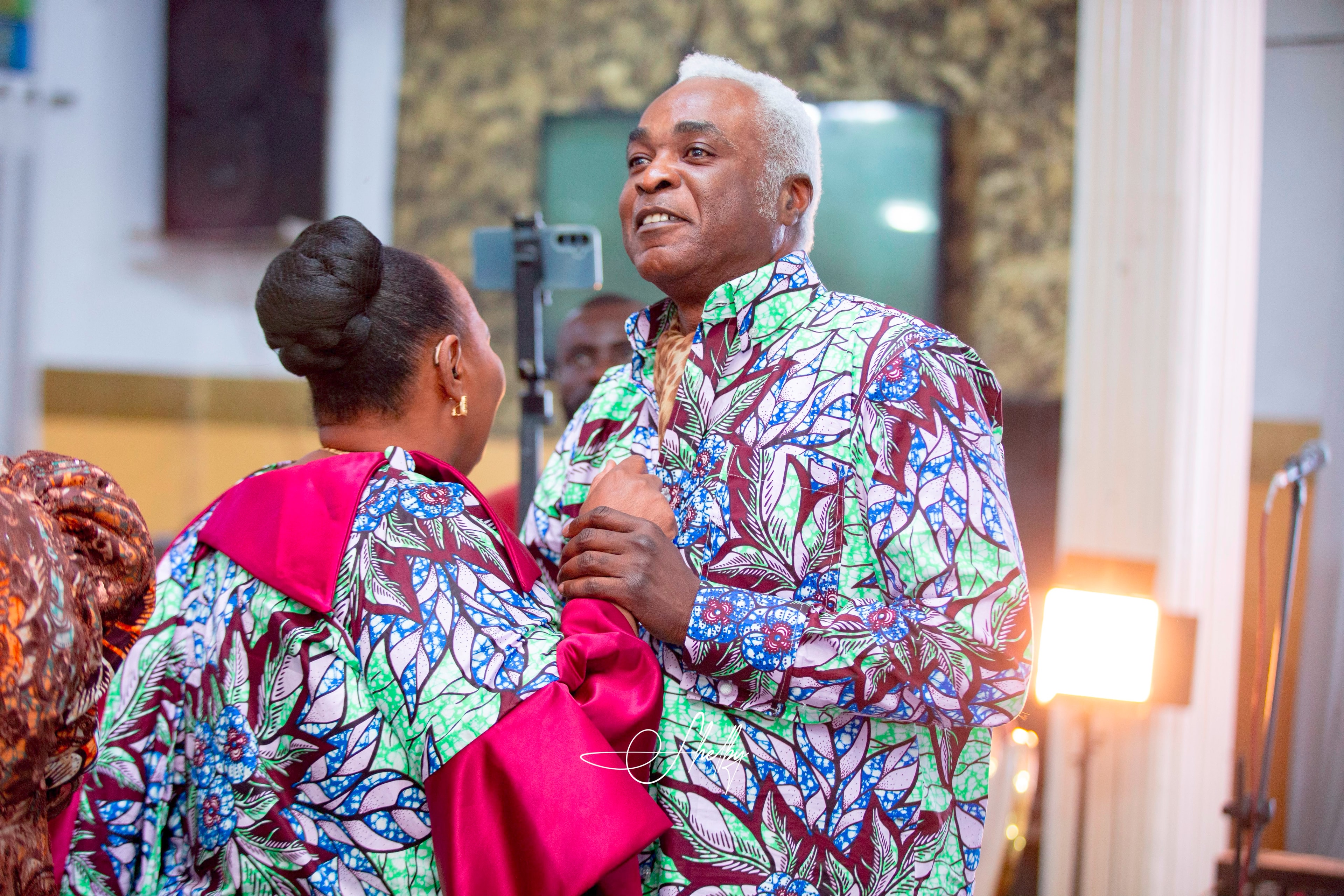 Parents in matching African print attire sharing a tender moment